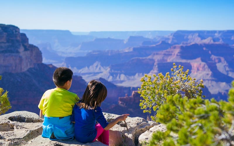 Viajar com crianças: destinos e dicas para ter uma viagem segura e tranquila 8 Imagem de duas crianças apreciando a vista do vale em uma viagem