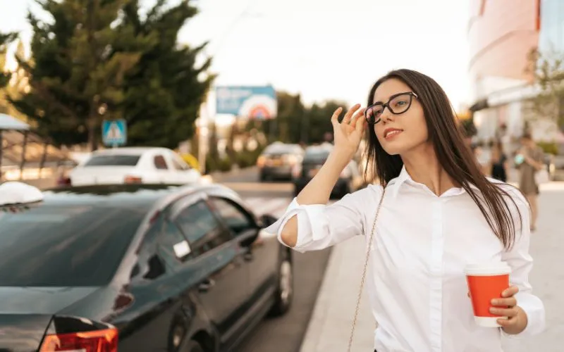 Foto de uma mulher olhando para o trânsito para chamar um taxi Foto de uma mulher olhando para o trânsito para chamar um taxi