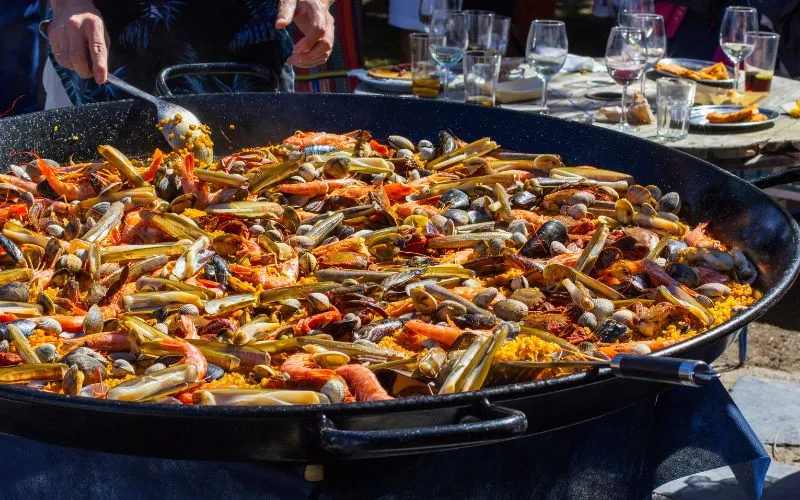 Homem cozinhando uma paella espanhola, frutos do mar, comida espanhola, arroz típico