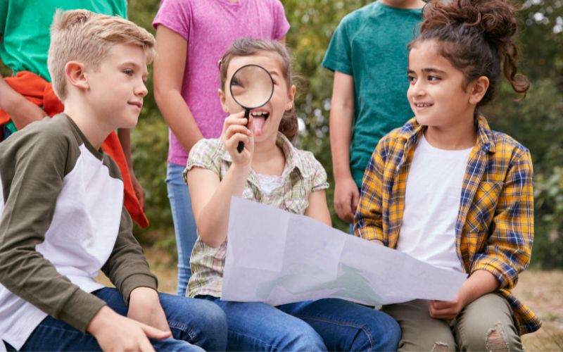 Viagem com crianças: Saiba por que e como escolher o melhor seguro para os menores 1 Grupo De Crianças Em Atividades Ao Ar Livre Camping Viagem Olhando Para Mapa Juntos