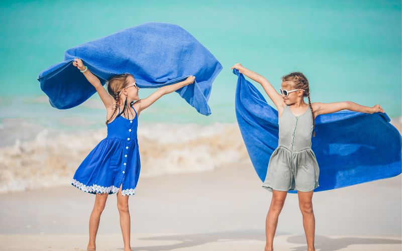 Descubra os Benefícios e Estatísticas das Viagens de Férias 7 As meninas se divertem com toalha de praia durante as ferias tropicais – Viagens de Férias,benefícios