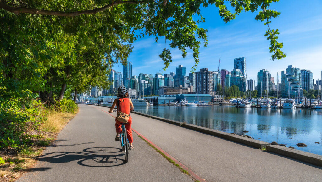 Copa do Mundo 2026 em Vancouver: guia completo para assistir aos jogos no BC Place 3 Turista andando de bicicleta com árvores ao redor, um lado do lado direito e a cidade ao fundo.
