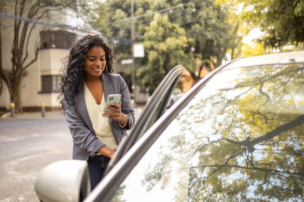 Mulher entrando em um carro enquanto mexe no celular