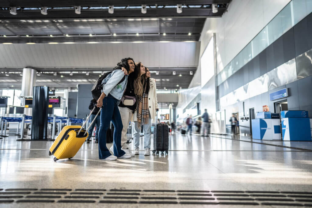 Custo de viagem internacional em 2026: como planejar cada despesa do seu roteiro 1 Amigos olhando para a programação aérea no aeroporto