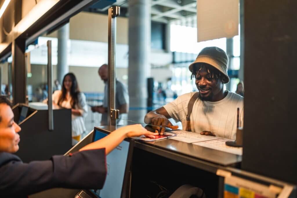 Checklist para viajar completo para viagens nacionais e internacionais 2 Passageiro masculino, negro e adulto fazendo check-in com confiança no aeroporto