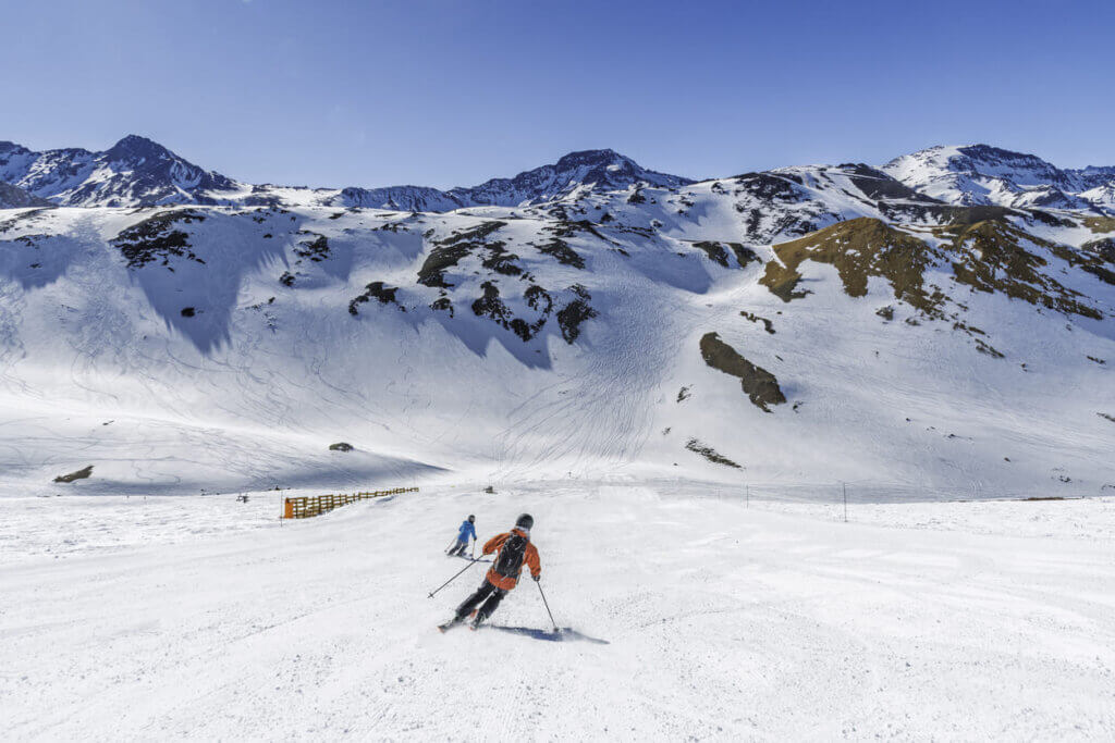 Custo de viagem para o Chile em 2026: quanto levar e como planejar 4 Pessoas esquiando no Valle Nevado, Chile, com céu azul