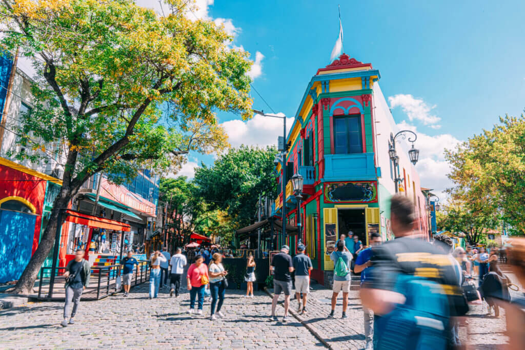 Custo de viagem para a Argentina em 2026: quanto levar e como planejar 3 Edifícios coloridos vibrantes e turistas em La Boca, Buenos Aires, Argentina