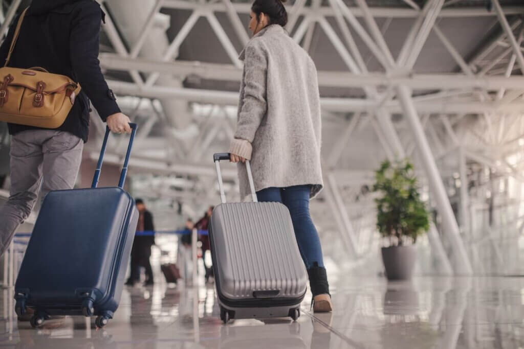 Checklist para viajar completo para viagens nacionais e internacionais 3 Jovem casal chegando ao aeroporto com malas de mão