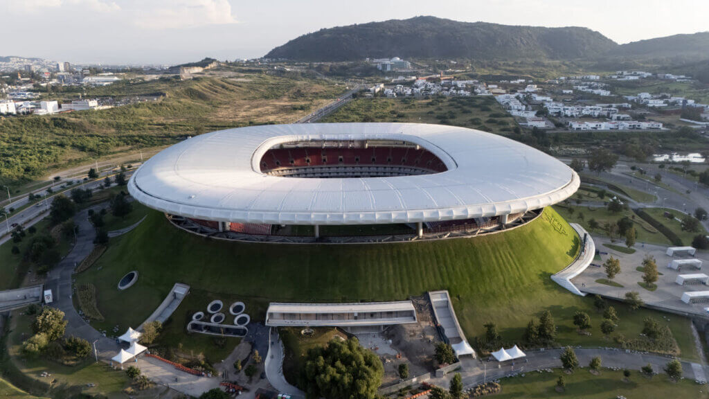 Vista aérea do estádio guadalajara em dia ensolarado com montanhas ao fundo.