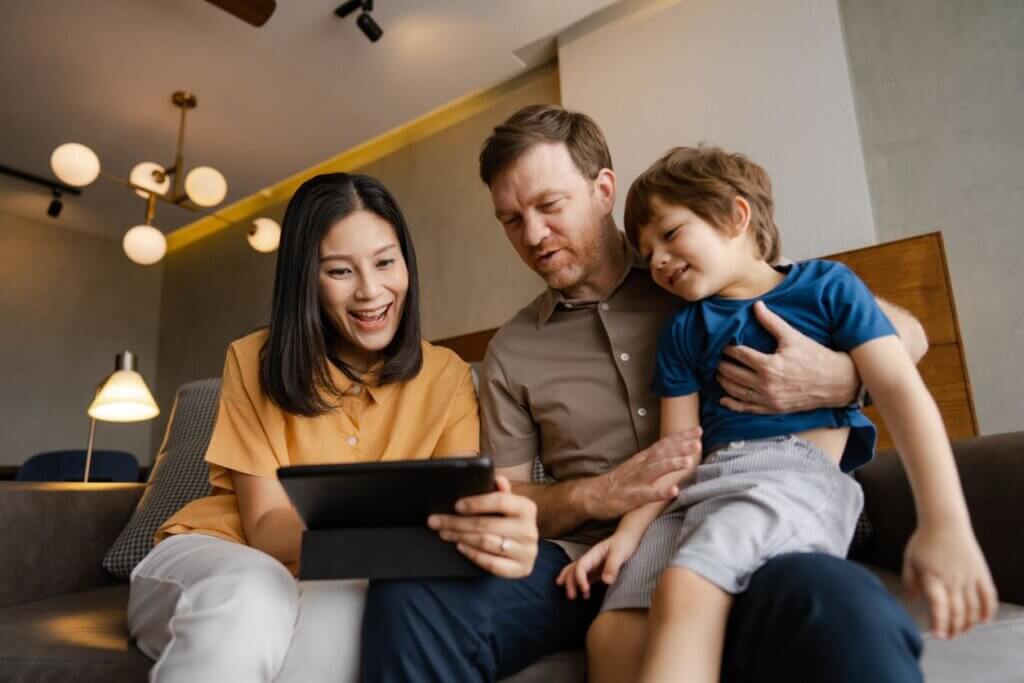 Seguro viagem familiar: quando compensa contratar em família em vez de individual 4 Família feliz programando viagem em sala de apartamento.