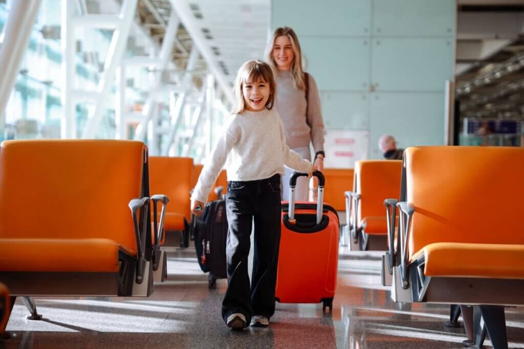 Seguro viagem familiar: quando compensa contratar em família em vez de individual 2 Mulher com menina e malas de viagem no aeroporto